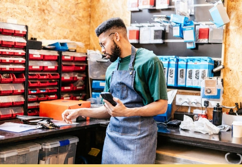 Small business owner checking a smartphone in his workshop